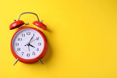 Photo of Red alarm clock on yellow background, top view. Space for text