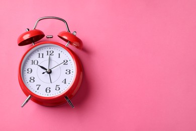 Photo of Red alarm clock on pink background, top view. Space for text