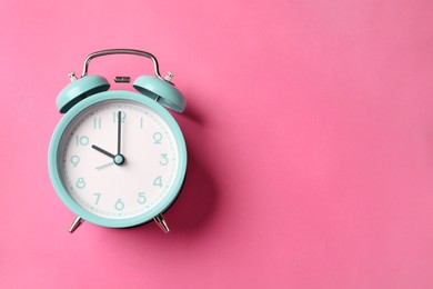 Photo of Turquoise alarm clock on pink background, top view. Space for text
