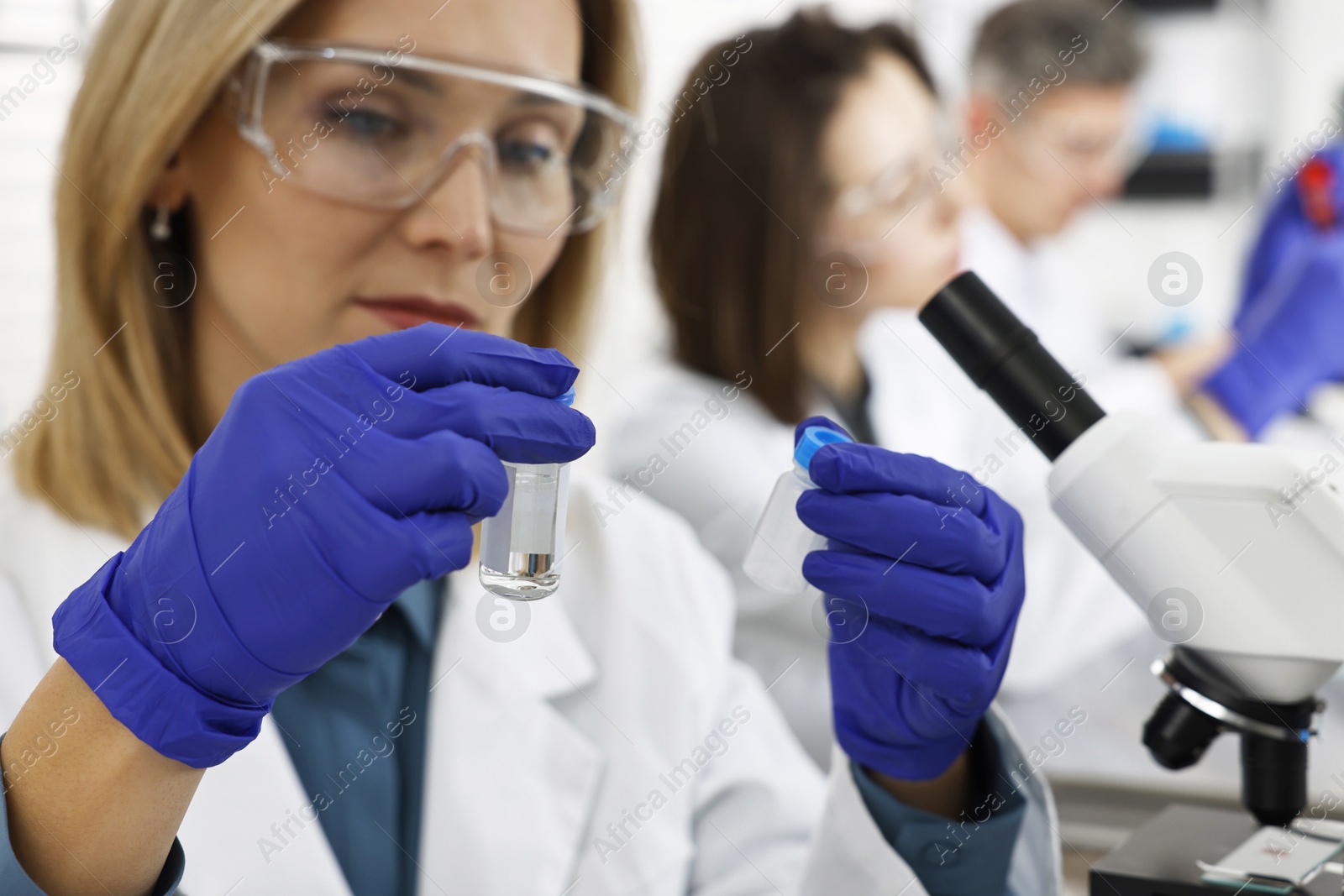 Photo of Scientist with vials working in laboratory, selective focus