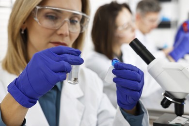 Photo of Scientist with vials working in laboratory, selective focus