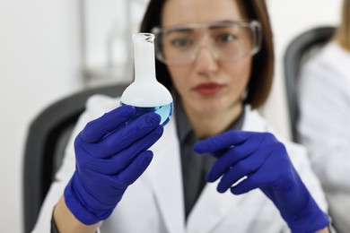 Photo of Scientist holding flask with sample in laboratory, selective focus