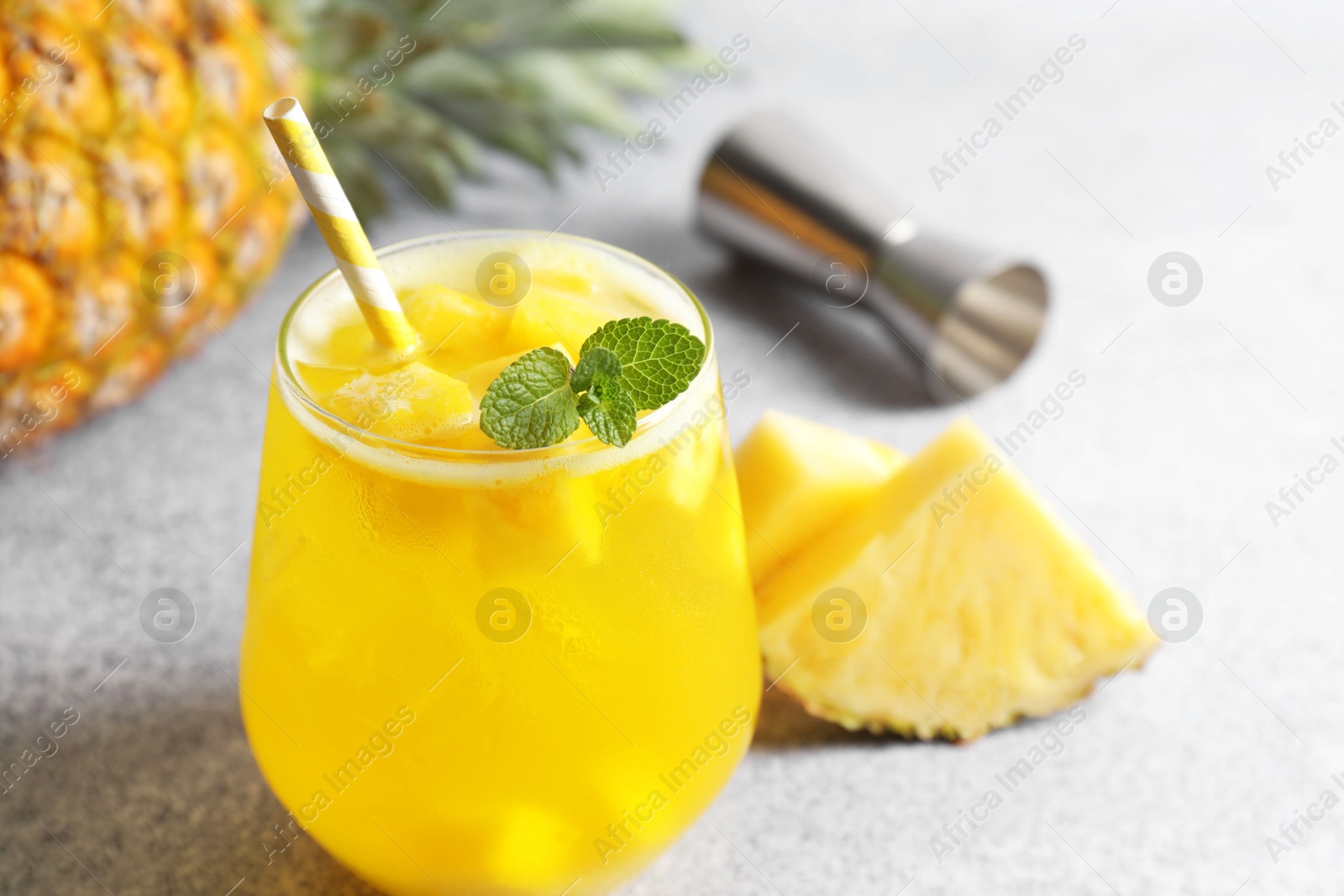 Photo of Tasty pineapple cocktail with mint in glass on gray table, closeup