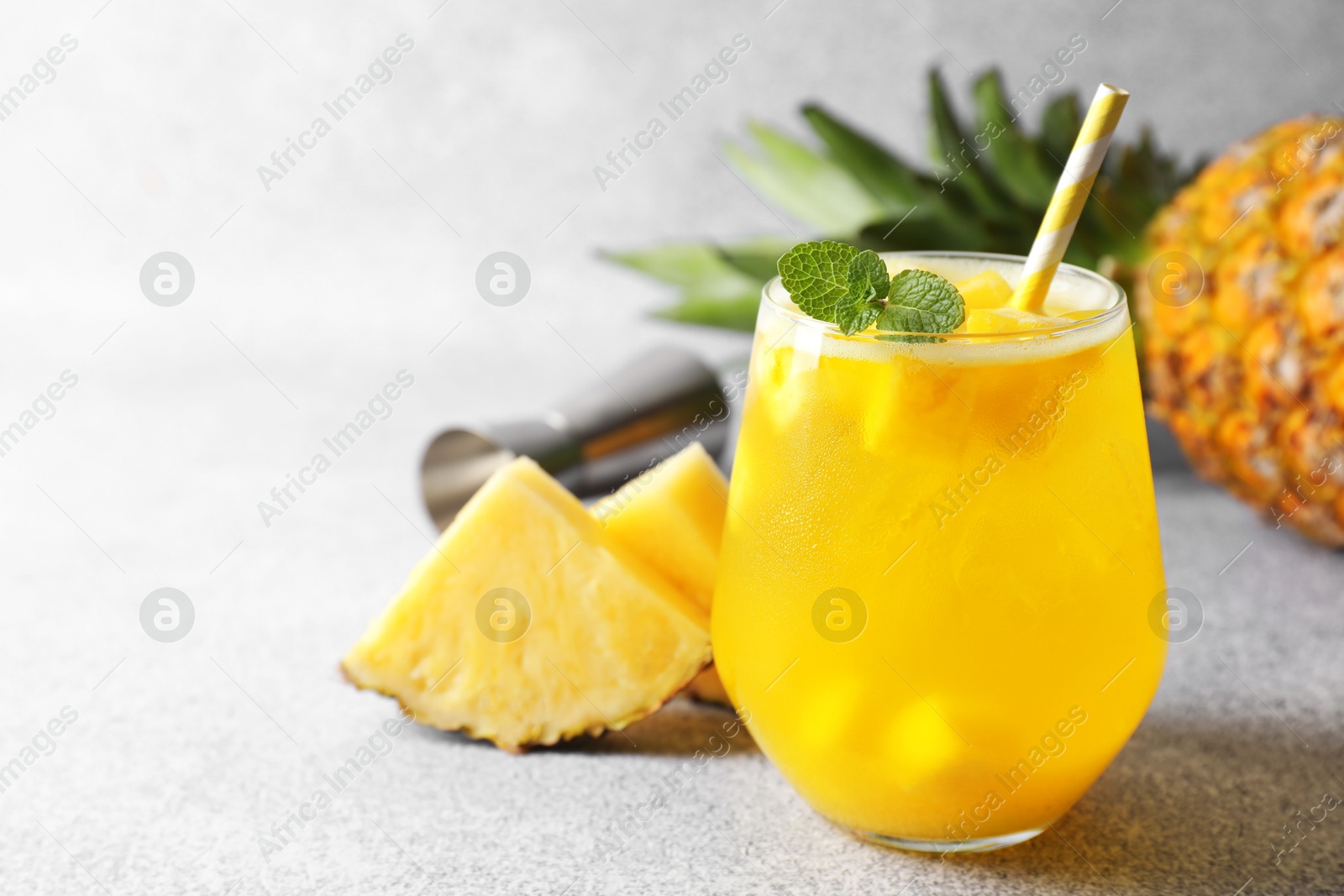 Photo of Tasty pineapple cocktail with mint in glass on gray table, space for text