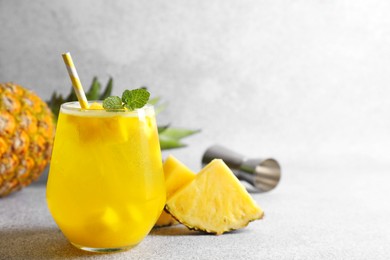 Photo of Tasty pineapple cocktail with mint in glass on gray table, space for text