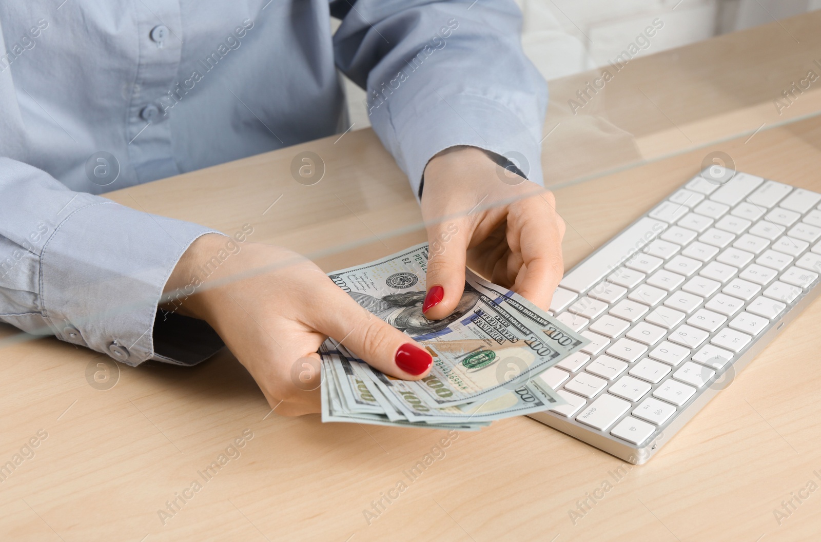 Photo of Woman with dollar banknotes at table in money exchange, closeup