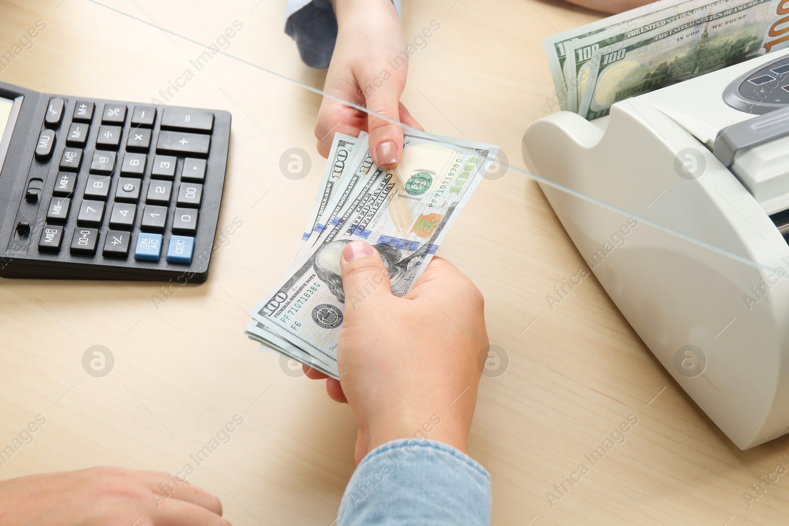 Photo of Client giving dollar banknotes to cashier at table in money exchange, closeup