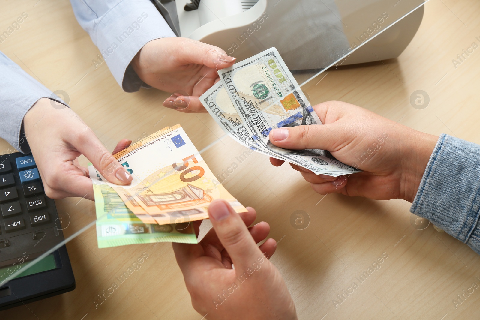 Photo of Client exchanging money at wooden table, closeup