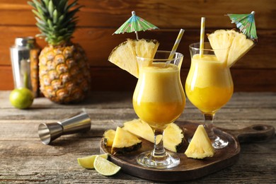 Photo of Tasty pineapple cocktail in glasses served on wooden table