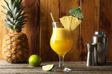 Photo of Tasty pineapple cocktail in glass served on wooden table