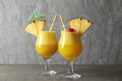 Photo of Tasty pineapple cocktail in glasses served on grey table