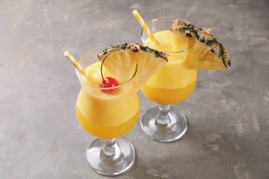 Photo of Tasty pineapple cocktail in glasses served on grey table