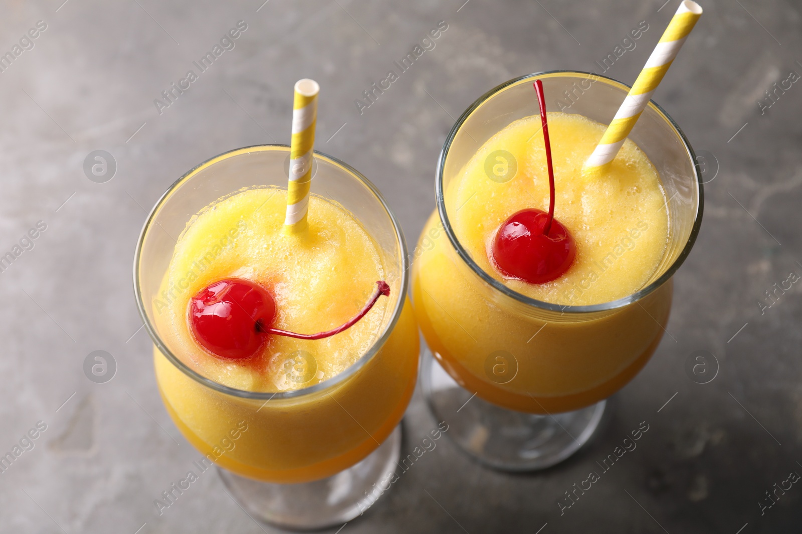 Photo of Tasty pineapple cocktail in glasses served on grey table, above view