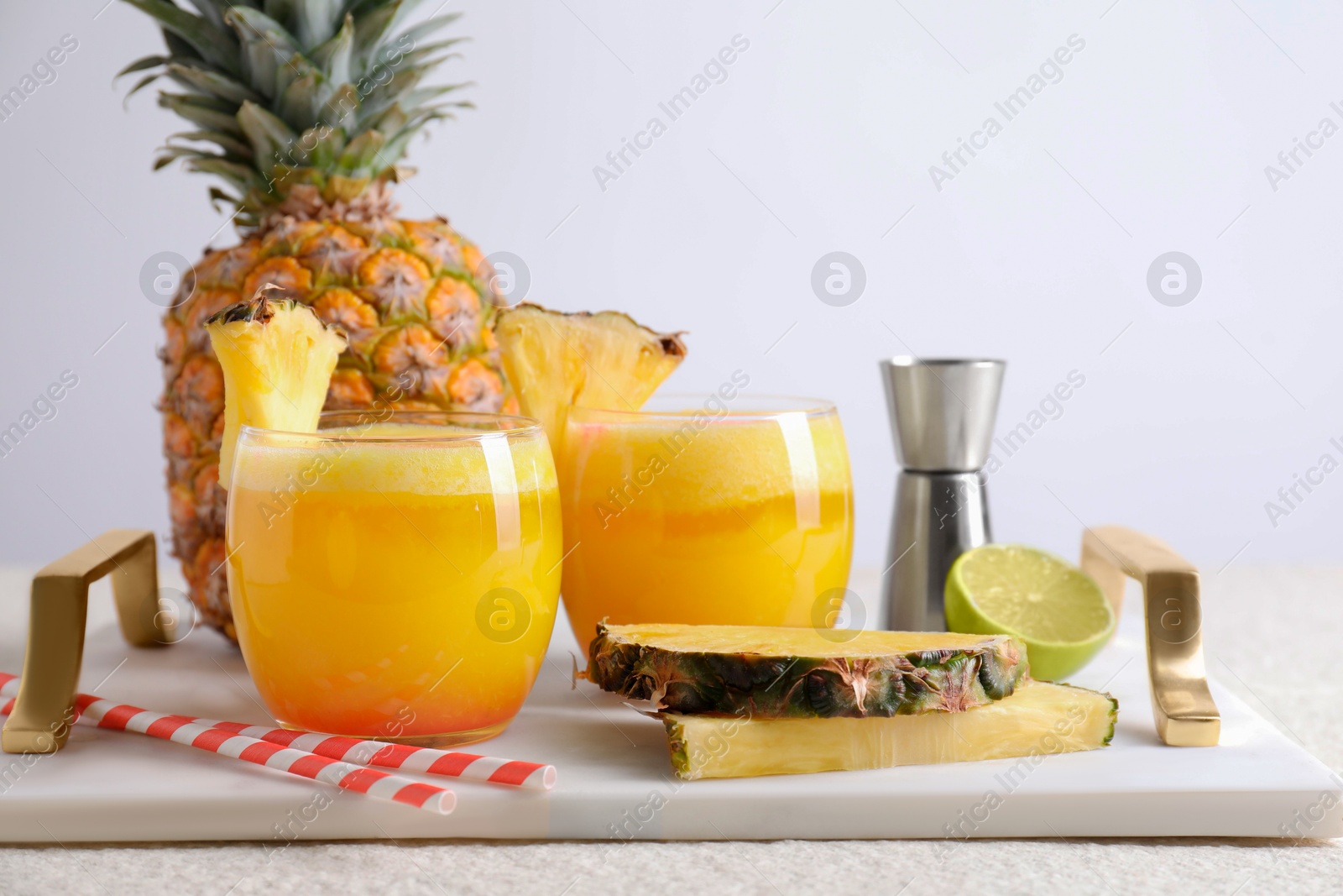 Photo of Tasty pineapple cocktail in glasses served on white table