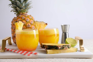 Photo of Tasty pineapple cocktail in glasses served on white table