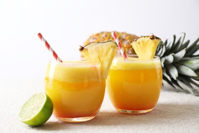 Photo of Tasty pineapple cocktail in glasses served on white table