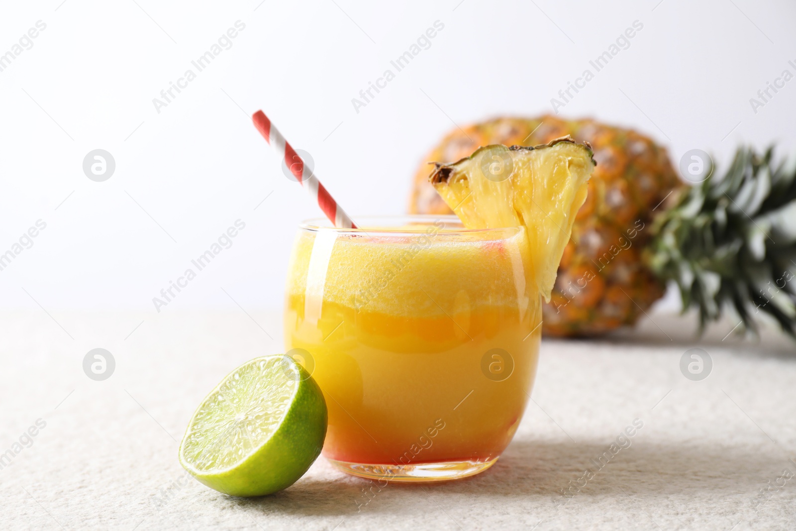 Photo of Tasty pineapple cocktail in glass served on white table, closeup