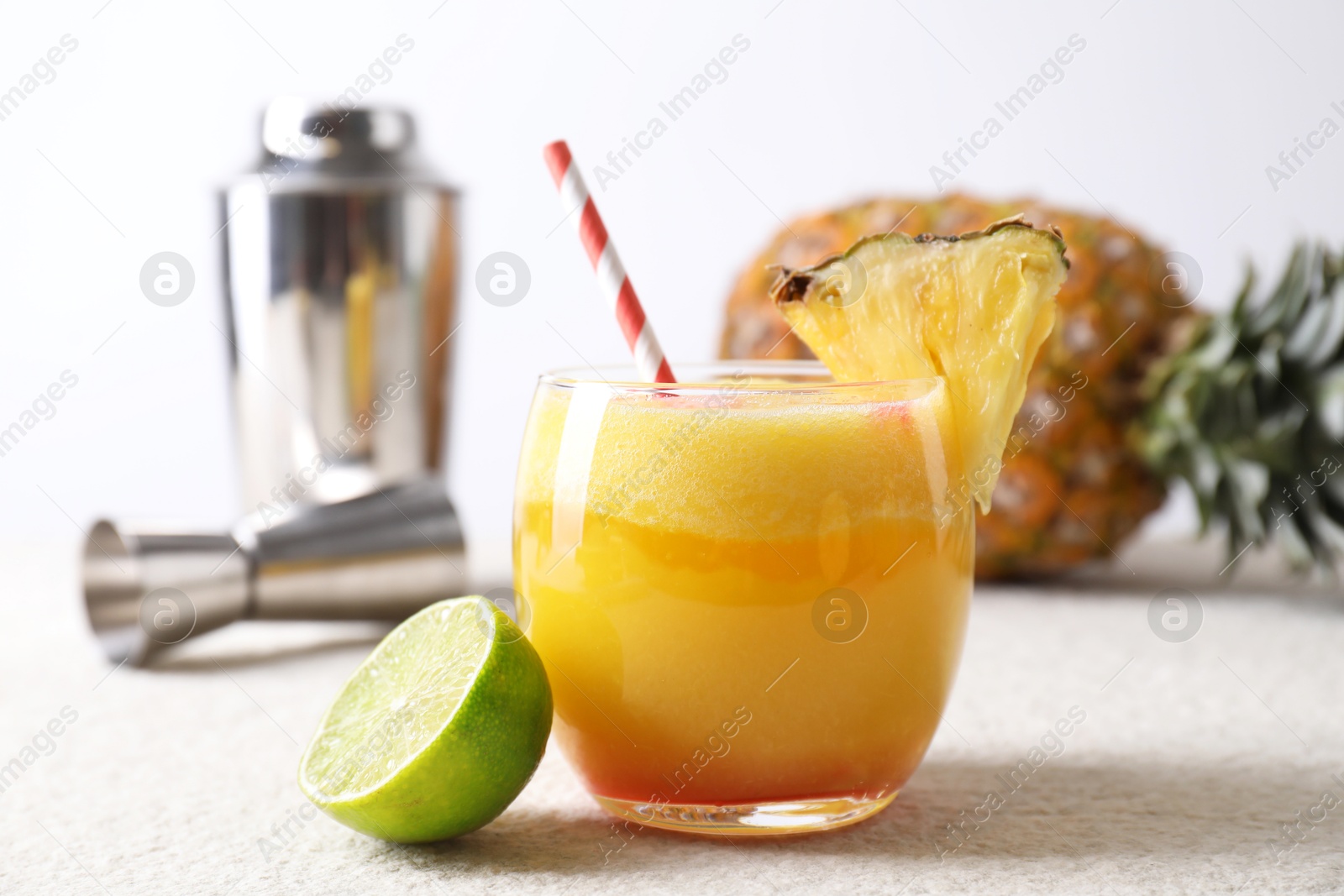 Photo of Tasty pineapple cocktail in glass served on white table, closeup