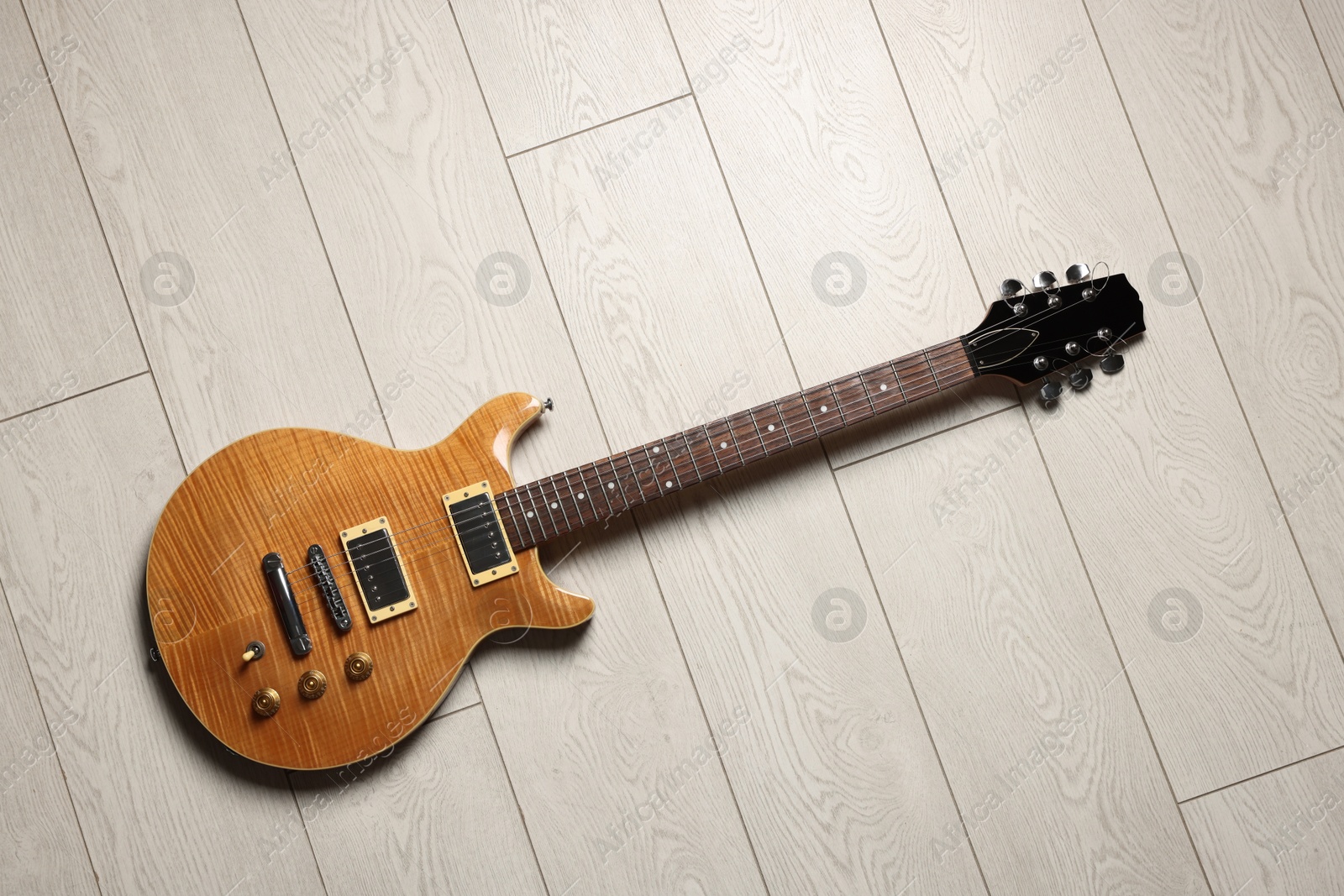 Photo of One modern electric guitar on light wooden background, top view