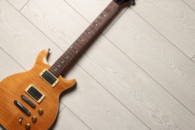 Photo of One modern electric guitar on light wooden background, top view. Space for text