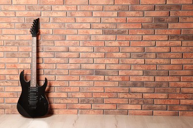 Photo of One modern electric guitar near brick wall. Space for text