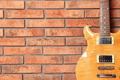 Photo of One modern electric guitar near brick wall, closeup. Space for text