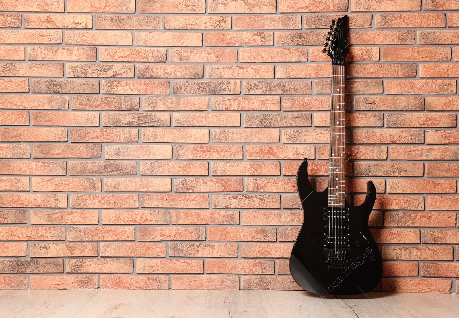 Photo of One modern electric guitar near brick wall. Space for text