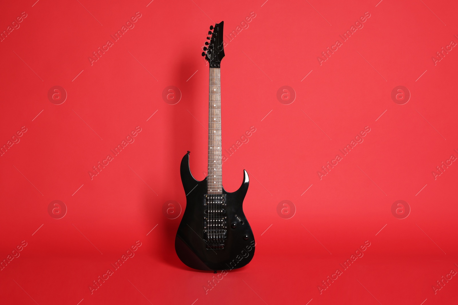 Photo of One modern electric guitar on red background