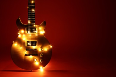 Photo of Electric guitar with Christmas lights on dark red background