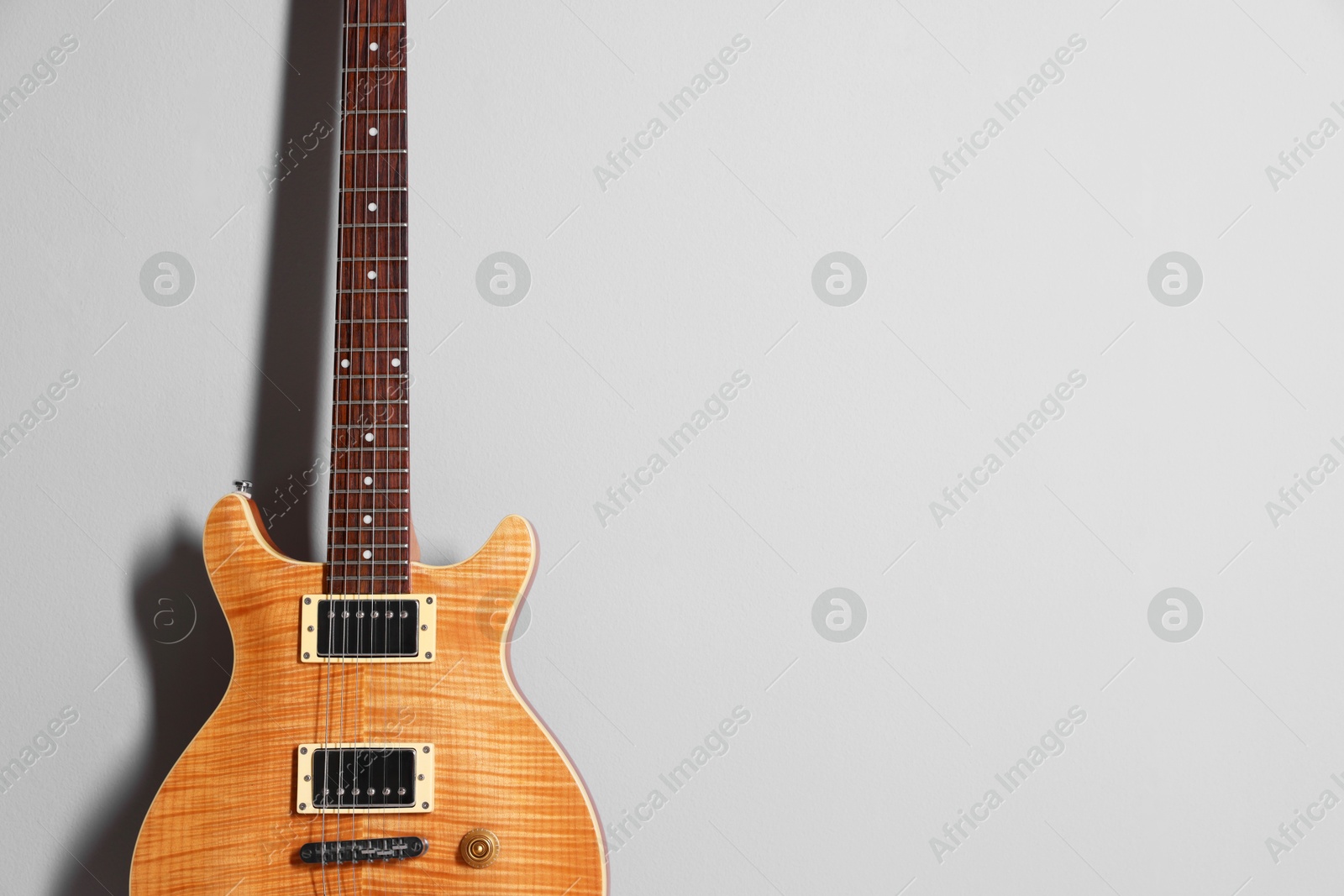 Photo of One modern electric guitar on light grey background. Space for text