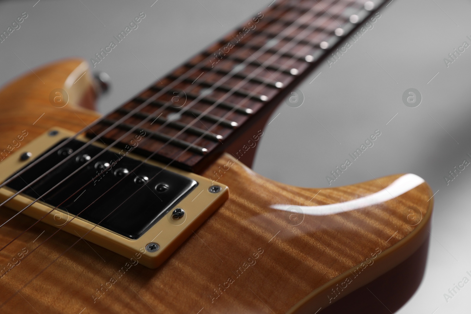 Photo of Modern electric guitar on grey background, closeup