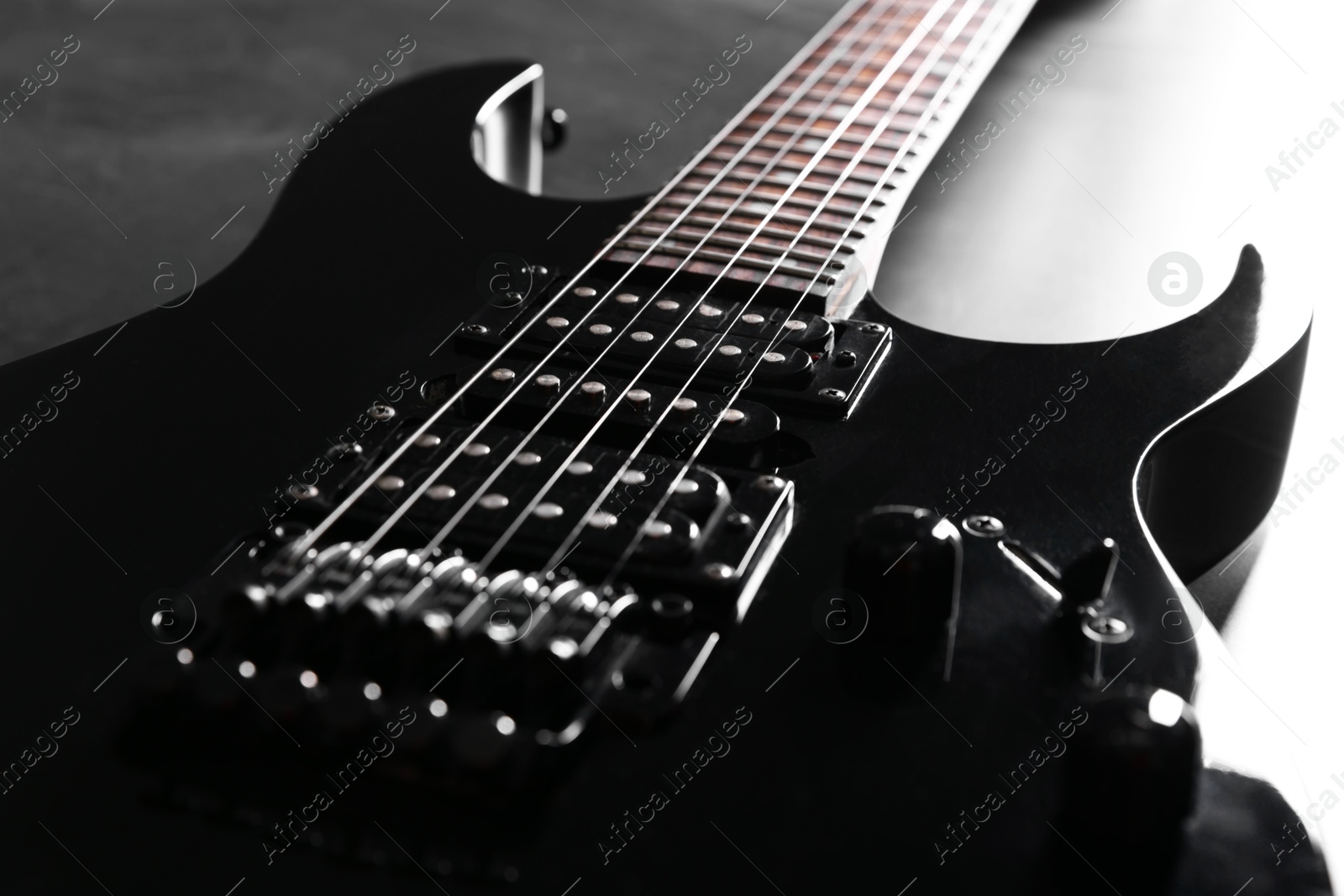 Photo of Modern electric guitar on black background, closeup