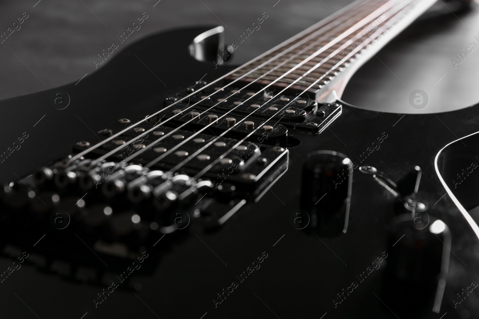 Photo of Modern electric guitar on black background, closeup