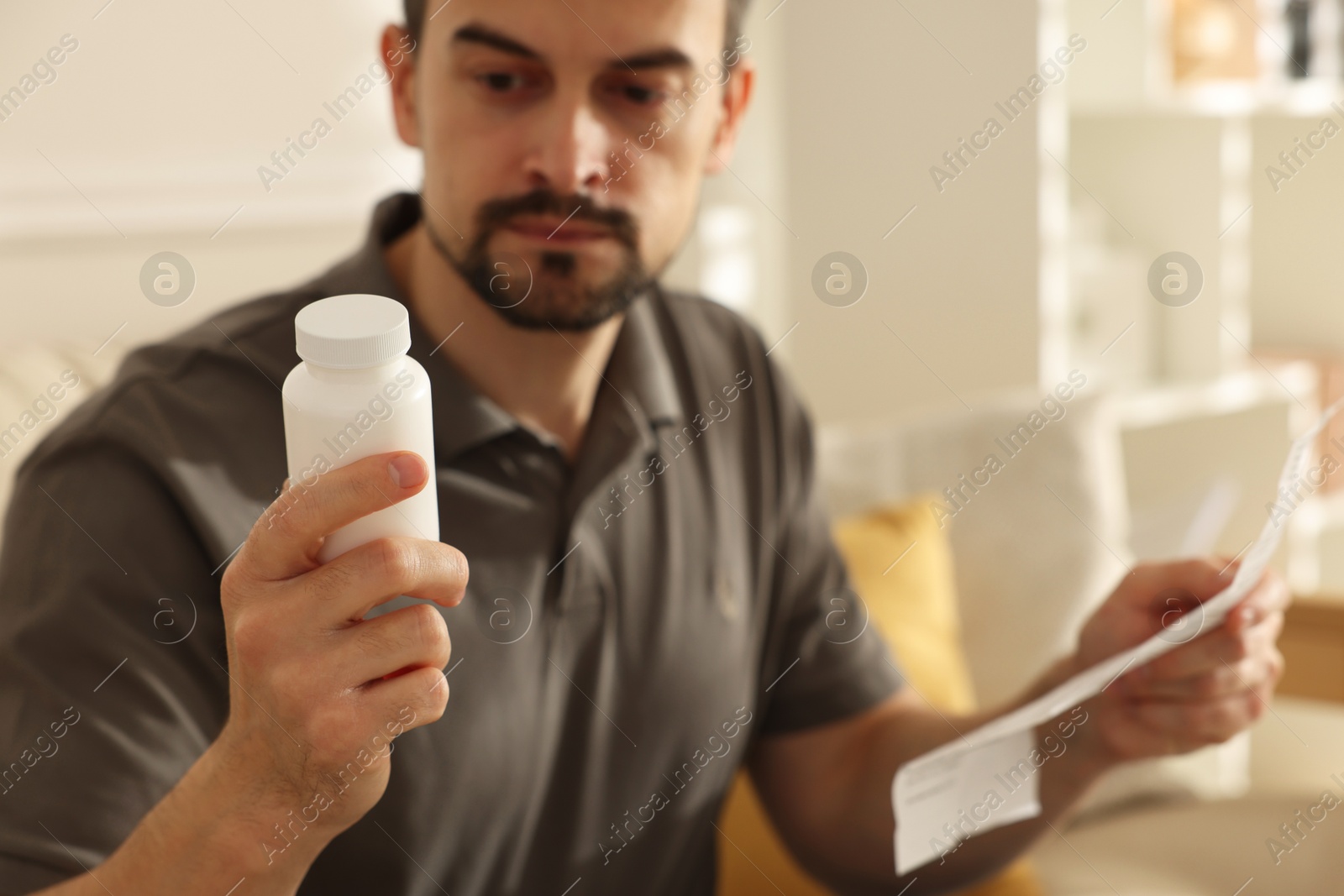 Photo of Man with pills and medical instruction at home, selective focus