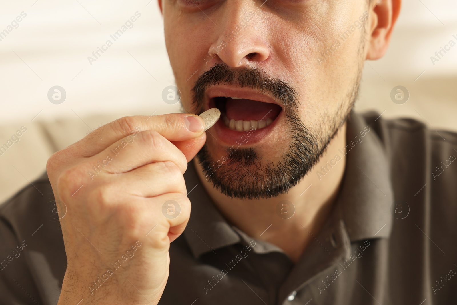 Photo of Man taking pill at home, closeup view