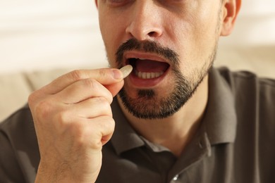 Photo of Man taking pill at home, closeup view