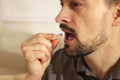 Photo of Man taking pill at home, closeup view