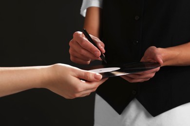 Photo of Singer signing autograph on vinyl record against black background, closeup