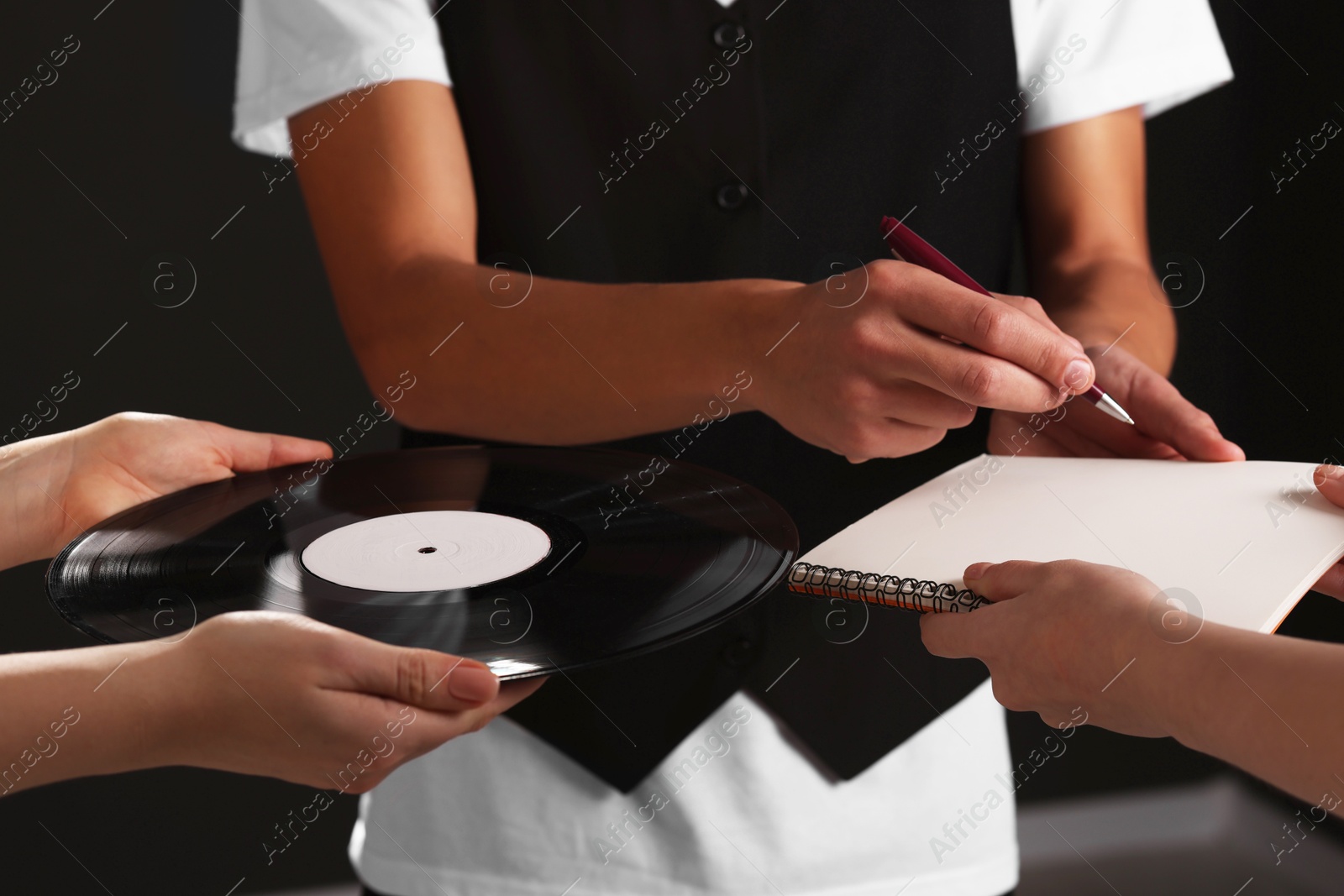 Photo of Singer signing autograph in notebook on black background, closeup