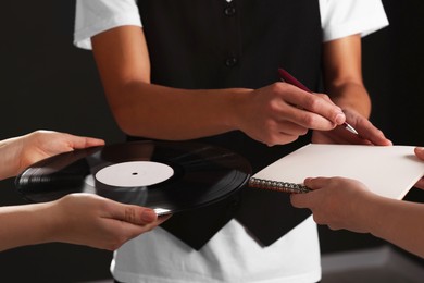 Photo of Singer signing autograph in notebook on black background, closeup