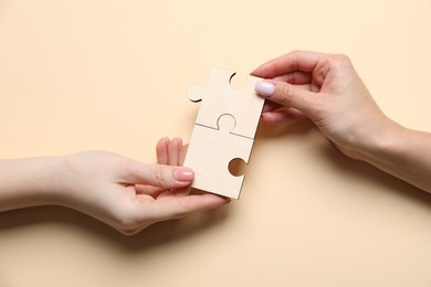 Photo of Business strategy and teamwork concept. Partners putting puzzle pieces together on beige background, top view