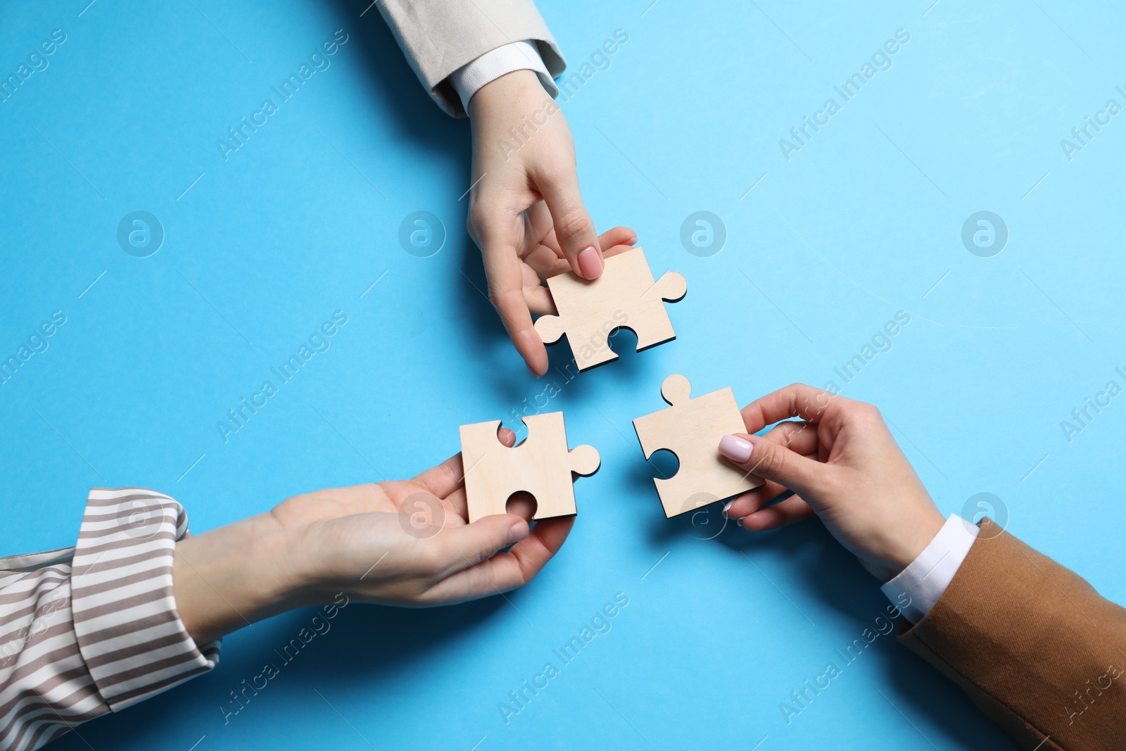 Photo of Business strategy and teamwork concept. Partners with different puzzle pieces on light blue background, top view