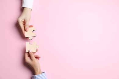 Photo of Business strategy and teamwork concept. Partners putting puzzle pieces together on pink background, top view with space for text