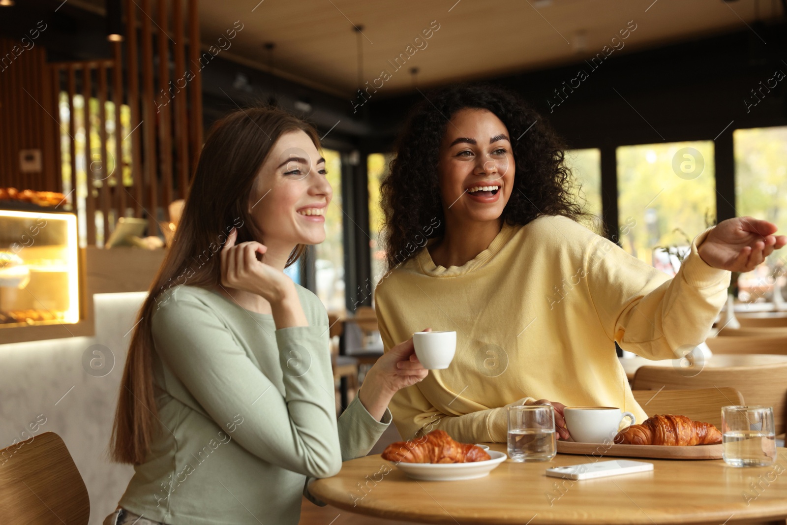 Photo of Happy women with coffee drinks chatting in cafe