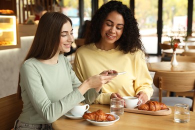 Photo of Woman taking picture of coffee drinks during meeting with her friends in cafe