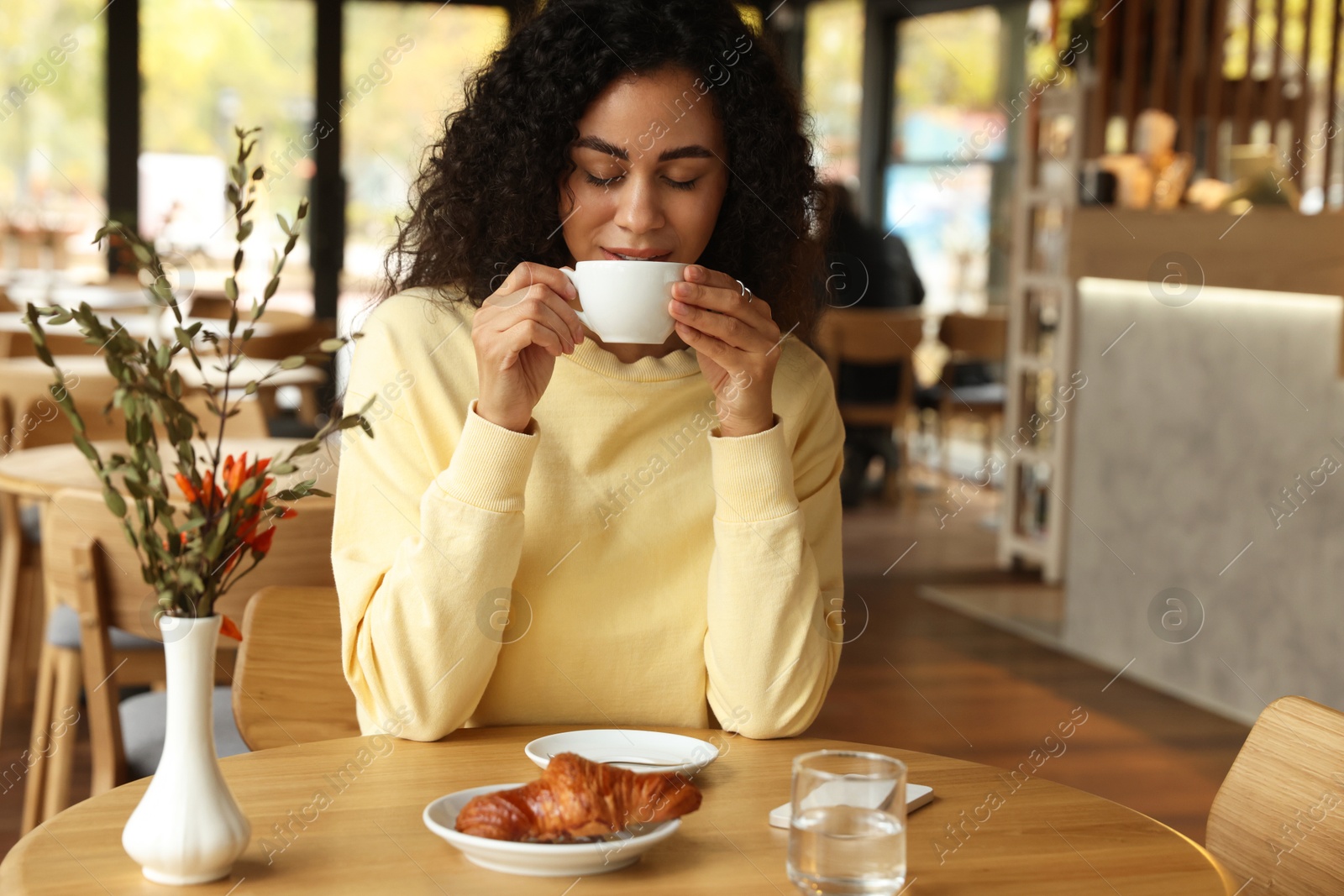 Photo of Woman enjoying her aromatic coffee at table in cafe