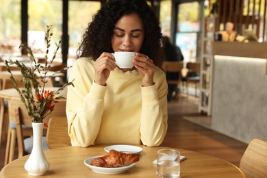 Photo of Woman enjoying her aromatic coffee at table in cafe