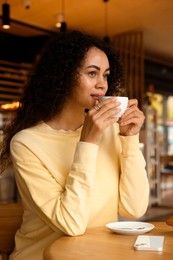 Photo of Woman enjoying her aromatic coffee at table in cafe