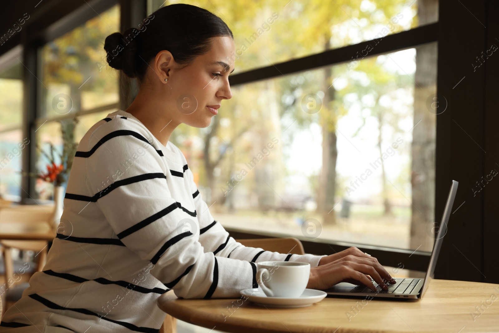 Photo of Woman working on laptop at table in cafe