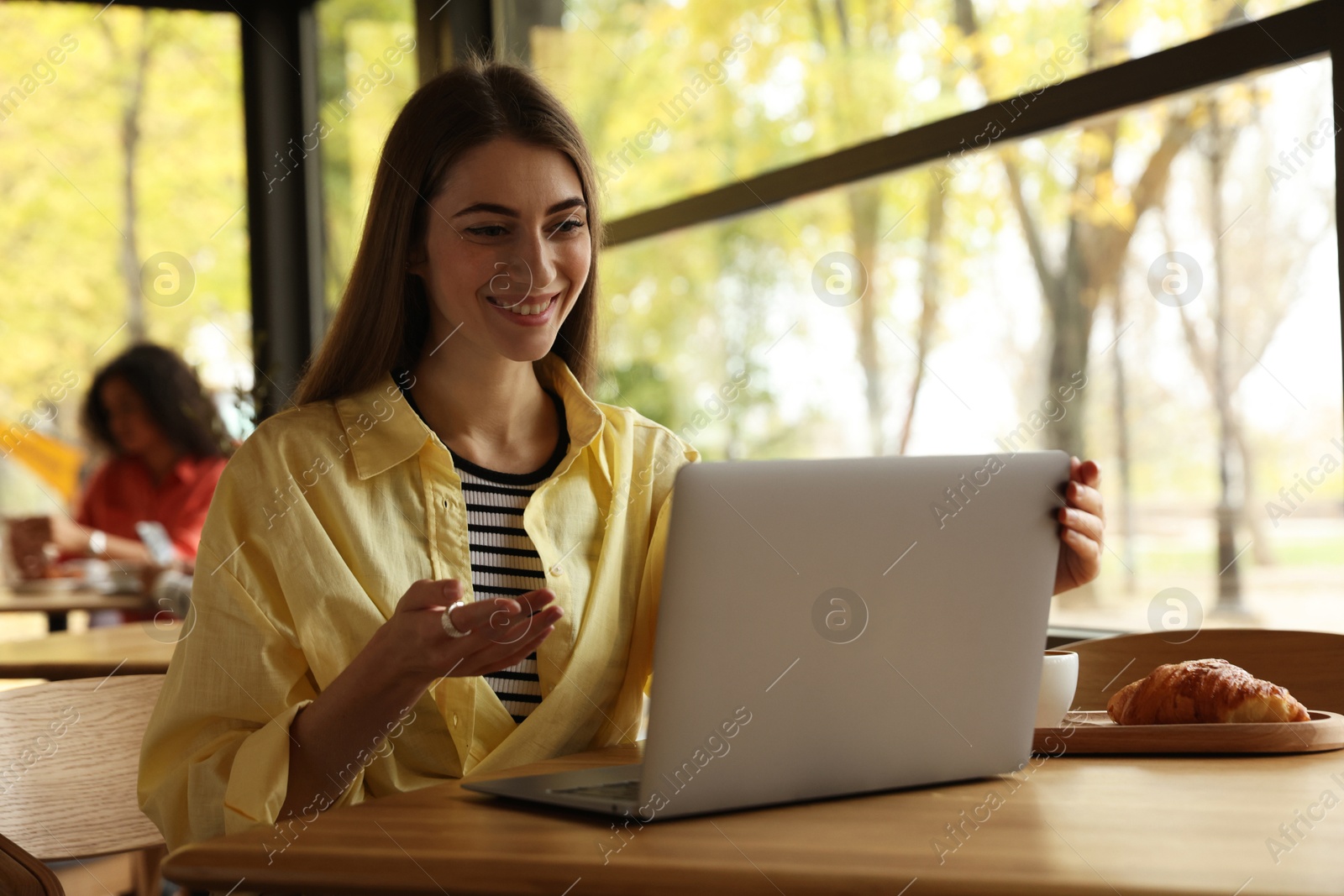 Photo of Woman working on laptop at table in cafe